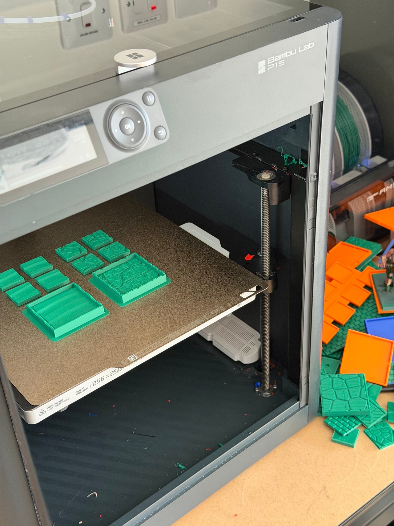 Bambu Lab P1S printer with green 3D-printed parts on its build plate.