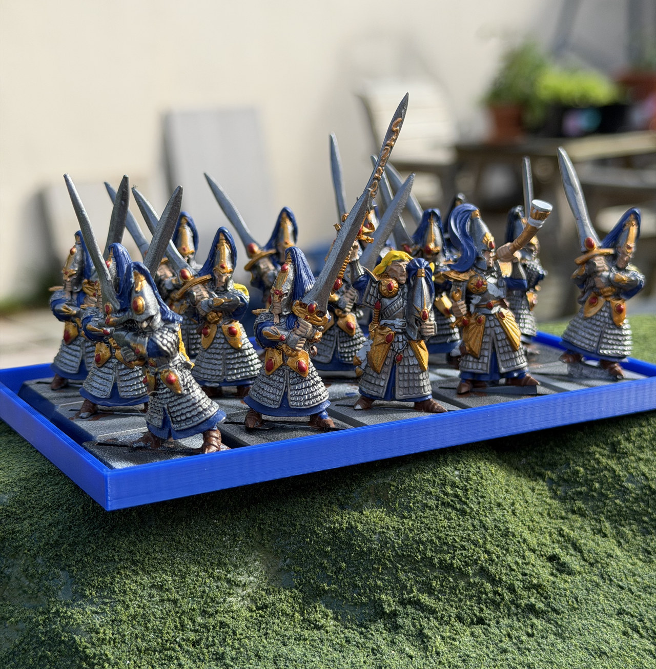 Painted tabletop models ranked on a real blue 3D-printed movement tray.